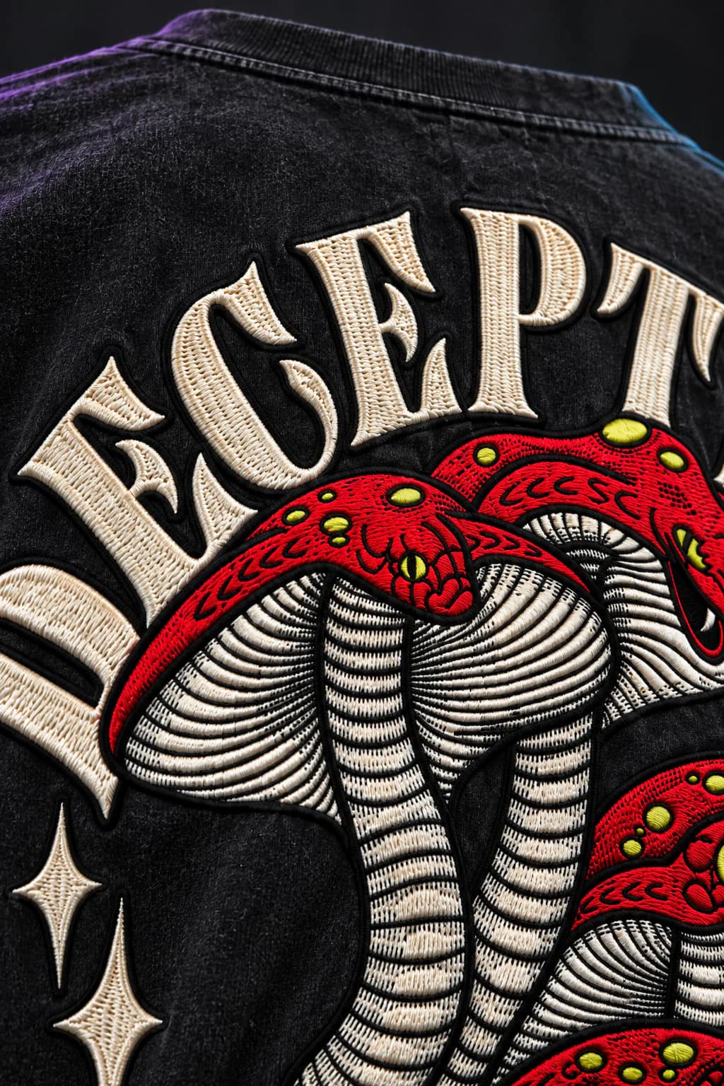 Macro view of scarlet, ivory and acid-yellow embroidery on washed-black jersey