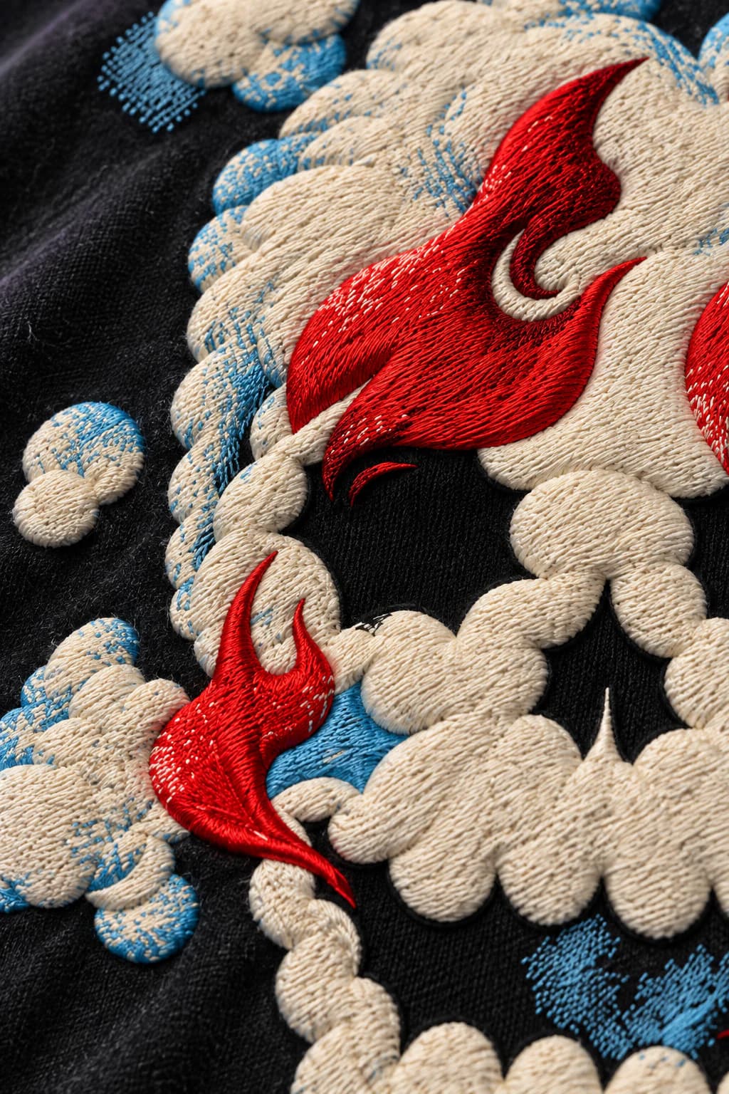 Macro detail of the ivory smoke and scarlet flame embroidery
